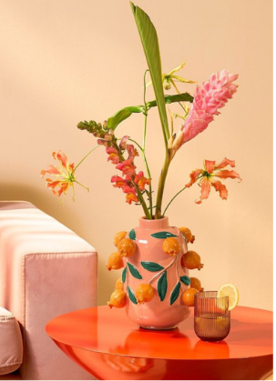 Florero con flores sobre mesa naranja