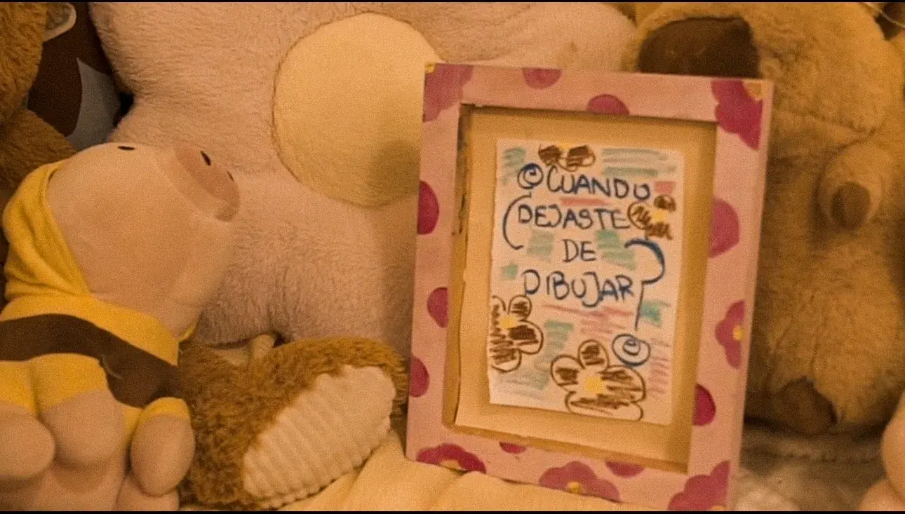 Fotograma: los peluches y el cuadro «cuando dejaste de dibujar»