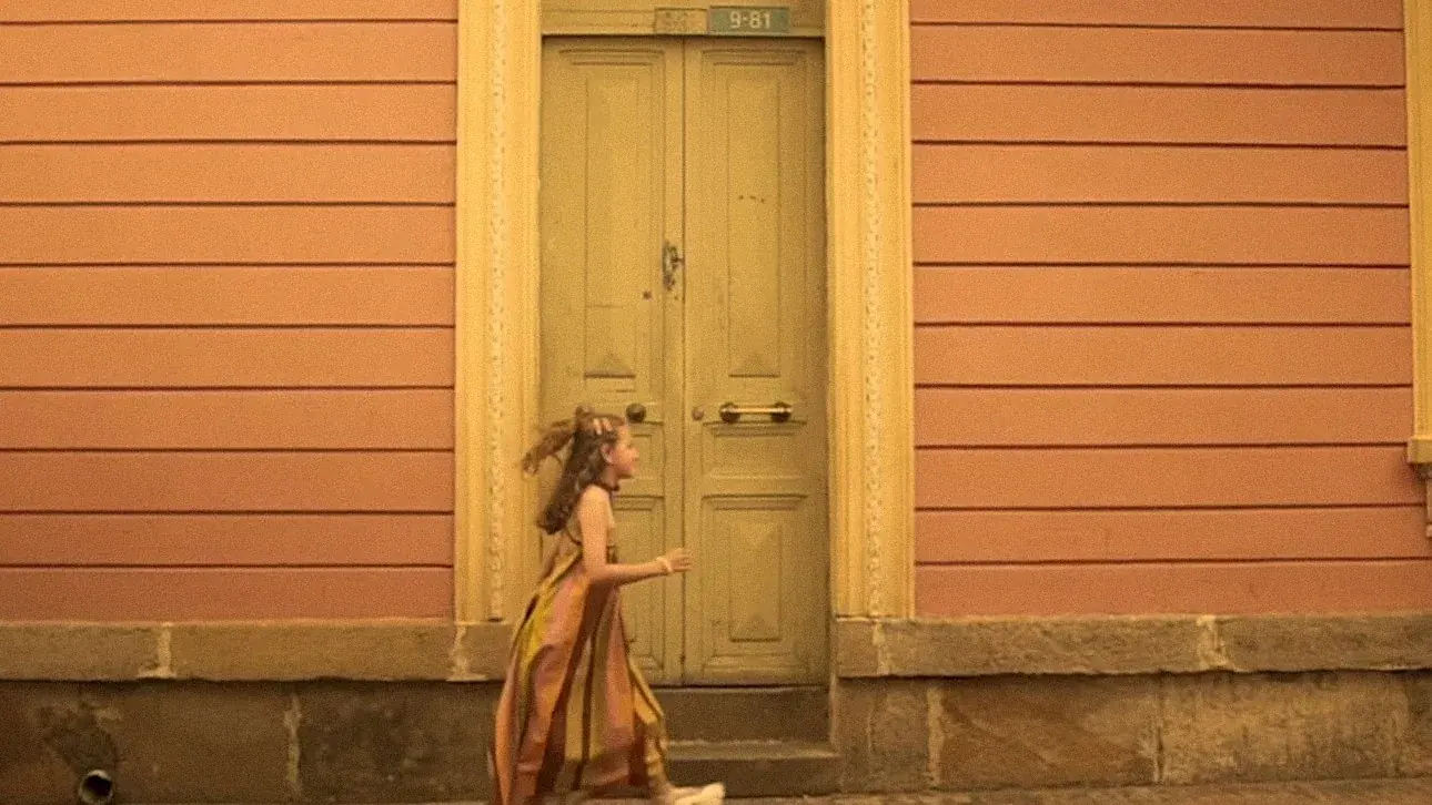 Fotograma: caminando frente a la puerta verde