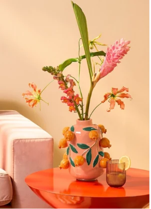 Florero con flores sobre una mesa naranja